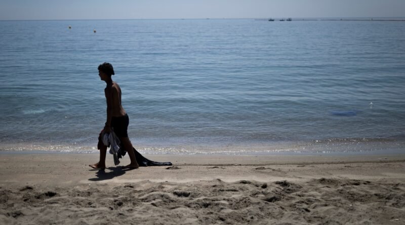 Un joven marroquí llegado a Ceuta recientemente recoge ropa del fondo del mar en la playa del Taraja, este viernes.