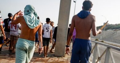 Dos hombres armados con un cuchillo (izquierda) y un palo siguen en Ceuta a un grupo de inmigrantes hacia la frontera con Marruecos el pasado día 31.